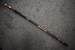 A stained bamboo walking cane, with turned wooden handle , stained decoration and drilled 'holes' gi