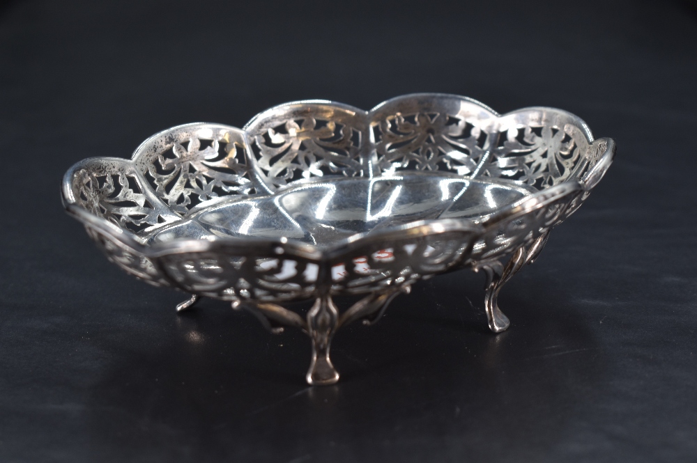 A small George V silver dish, of lobed and fluted oval form with foliate pierced border, raised on