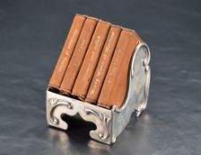 An unusual Edwardian miniature silver book stand, of Art Nouveau scrolling design containing five