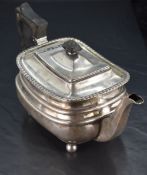A George V silver teapot, of rounded rectangular form with hined finial topped cover within a