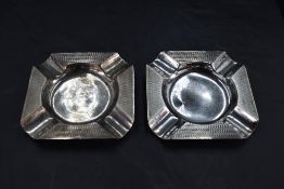 A pair of George V silver ashtrays, of canted square form with central circular well enclosed by