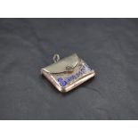 A George V silver an enamel stamp case, formed as a clutch bag with hinged cover and worded 'stamps'
