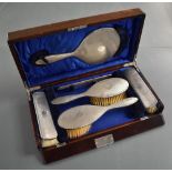 A George VI cased and silver mounted brush set, comprising hand mirror, two hair brushes, two