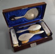 A George VI cased and silver mounted brush set, comprising hand mirror, two hair brushes, two