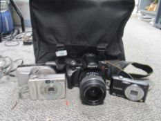 A collection of cameras, including Panasonic Lumix, Sony A 230 and Canob Ixus Z90.