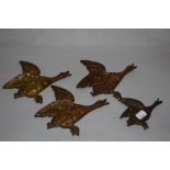 A group of four graduating cast metal flying geese ornaments, the largest measuring 19cm long