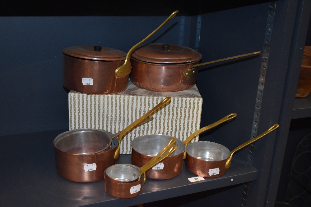 Two vintage copper and brass sauce pans, together with a harlequin set of graduating pans of similar