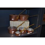 Two vintage copper and brass sauce pans, together with a harlequin set of graduating pans of similar