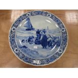 A 20th century large Delft blue charger, having scene of women and children on shore, with sailing
