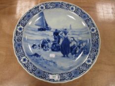 A 20th century large Delft blue charger, having scene of women and children on shore, with sailing