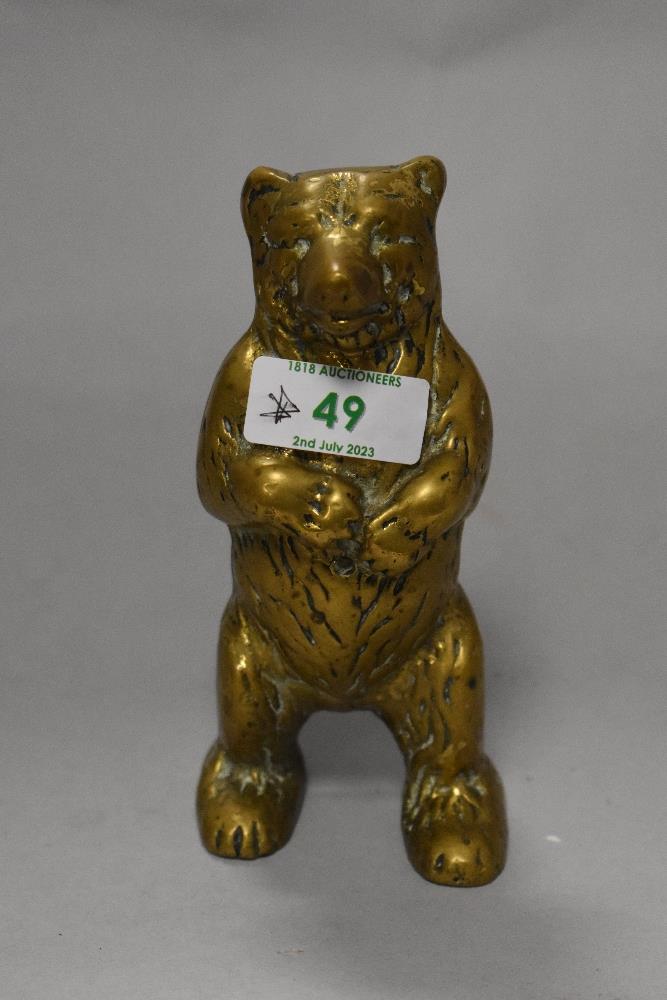 An antique brass money box in the form of a bear.