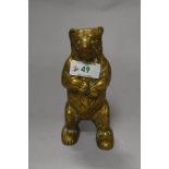 An antique brass money box in the form of a bear.