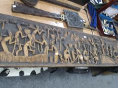 A large carved African wall hanging, having traditional scene of figures at work.