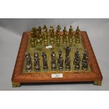 A brass chess board with wood edge and carved Greek key pattern, with Greek God and