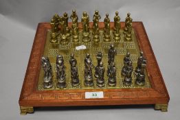 A brass chess board with wood edge and carved Greek key pattern, with Greek God and
