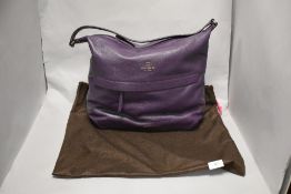 A purple leather Kate Spade, New York handbag, appears to be unused, with care advice card present.