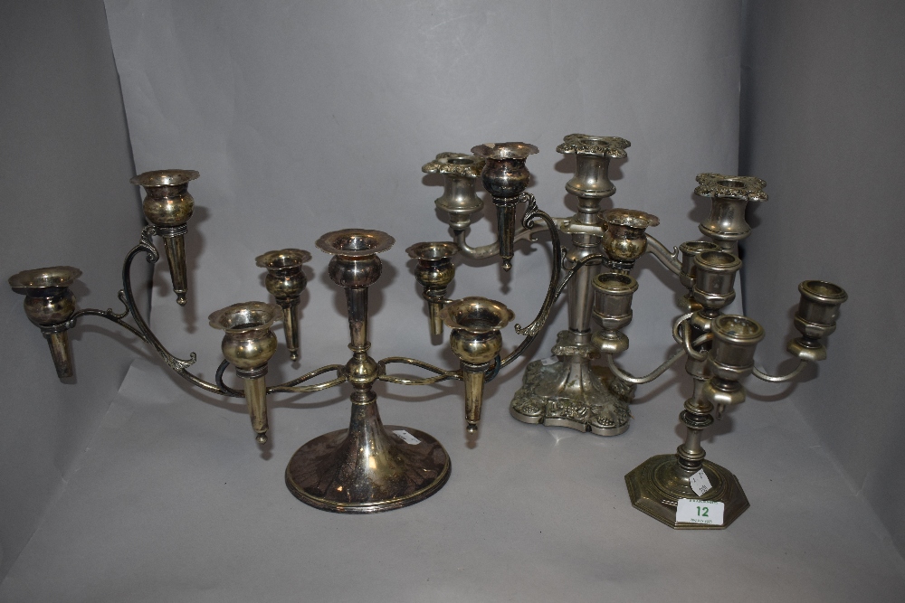 Three silver plated candelabras, the largest measuring 25cm tall and 46cm across