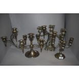 Three silver plated candelabras, the largest measuring 25cm tall and 46cm across