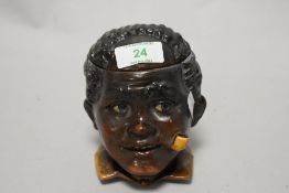 A novelty pottery tobacco jar, modelled as a Blackamoor smoking a pipe, 12cm tall