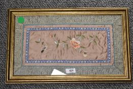 A framed and glazed Chinese embroidery having bird and blossom depicted in silk thread to centre.