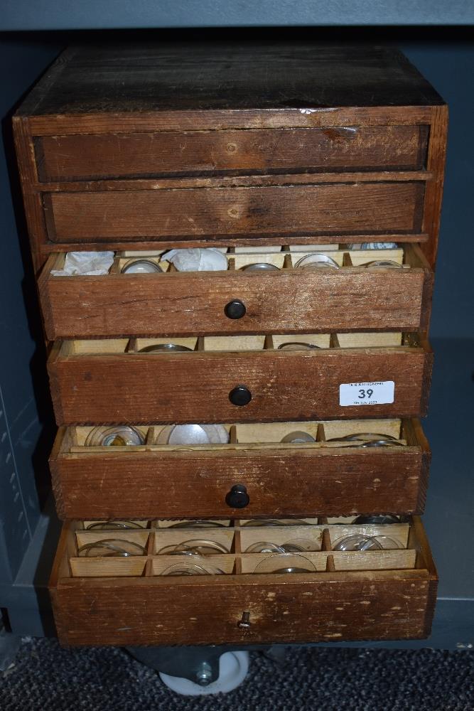 An early 20th century pine cabinet, housing a large collection of optometrists glass lenses.