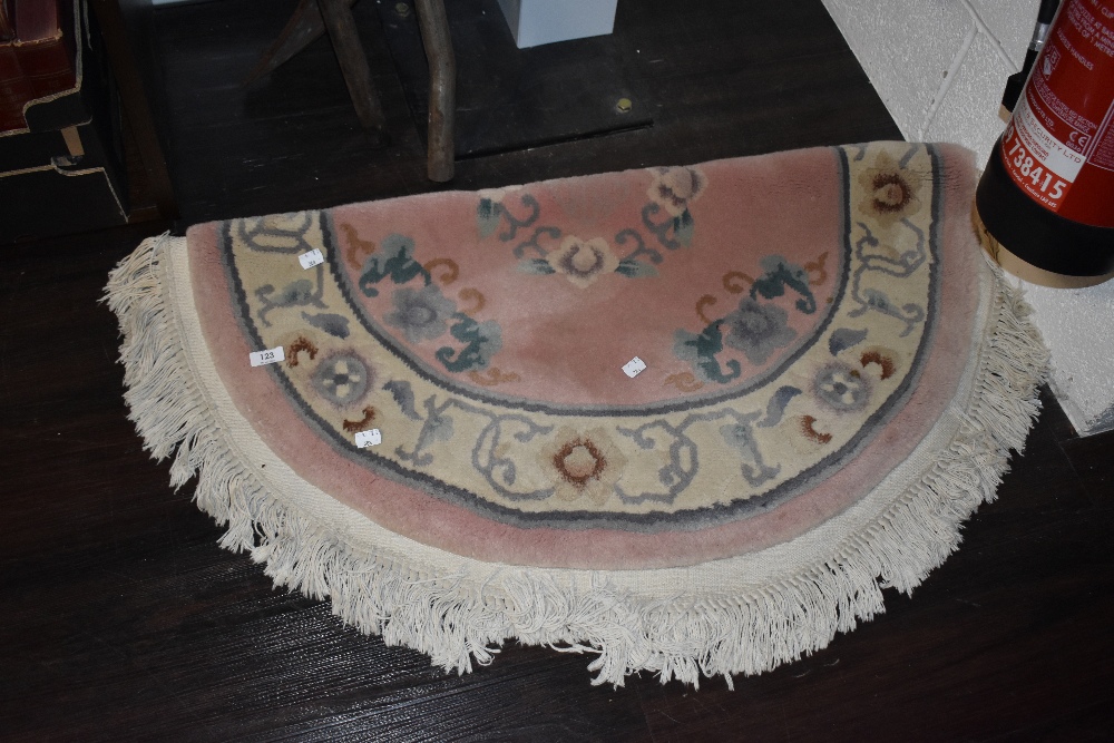 A traditional Chinese rug, in pink, grey and green tones, having fringed edge.