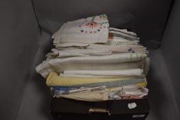 A box full of vintage table linen etc, including embroidered and crotchet edged examples.