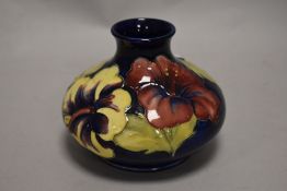 A mid century Moorcroft vase of squat baluster from, having tube lined hibiscus pattern on cobalt