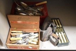 A vintage Adey's cigar box containing cutlery, two flat irons, plus two other boxes of cutlery
