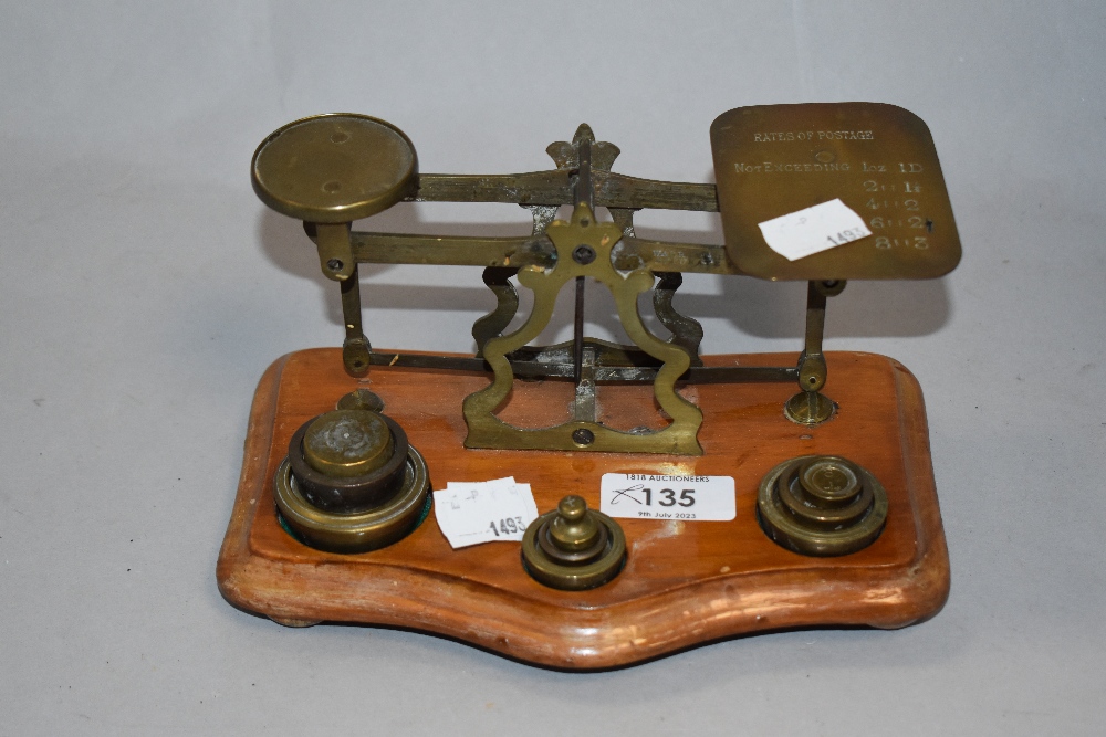 A set of vintage brass postal scales with weights, sat on wood base.