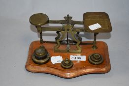A set of vintage brass postal scales with weights, sat on wood base.
