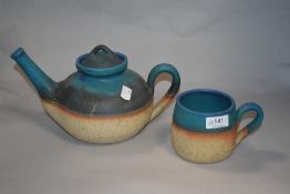 A studio pottery teapot and mug, having teal blue banded glaze to natural ground.