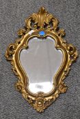 A reproduction Rococco style wall mirror with ornate gilt frame, measuring 50cm tall