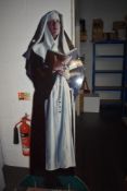 A life size cardboard nun, mounted on thick board.