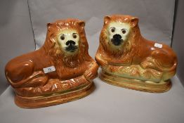 A pair of Victorian Staffordshire Pottery recumbent lion fireside ornaments, having applied glass