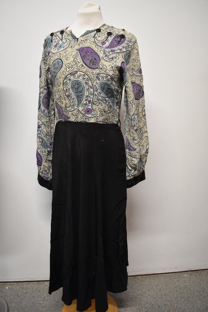 A 1940s dress, having paisley patterned bodice and black skirt, long sleeves and button details to