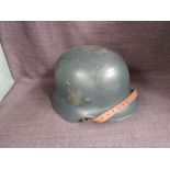 A German WWII Steel Helmet, dark grey/blue, leather liner and chin strap, decal badge removed, sized