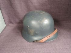 A German WWII Steel Helmet, dark grey/blue, leather liner and chin strap, decal badge removed, sized