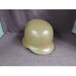 A German WWII Steel Helmet having leather liner and chin strap, possible sand/yellow/buff colour