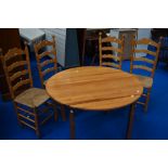 A vintage pine circular kitchen table and four ladderback chairs having seagrass type seats