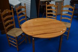 A vintage pine circular kitchen table and four ladderback chairs having seagrass type seats