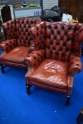 A pair of red leather button back wing armchairs