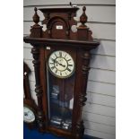 A Victorian Vienna style wall mounted clock with an enamel face and carved mahogany frame.