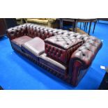 A traditional red leather three seater chesterfield settee and footstool