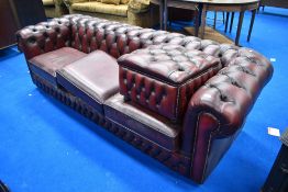 A traditional red leather three seater chesterfield settee and footstool
