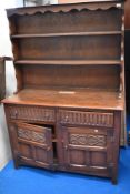 A Priory Oak style dresser, of traditional arrangement with plate rack over drawers and cupboards,