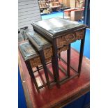 An Oriental nest of three tables with carvings to frieze and under glass to top