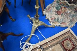 An early 20th century standard lamp in brass on tripod base with adjustable shaft.