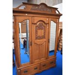 A 19th Century golden oak double mirror door wardrobe having carved pediment and similar pegged