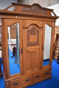 A 19th Century golden oak double mirror door wardrobe having carved pediment and similar pegged